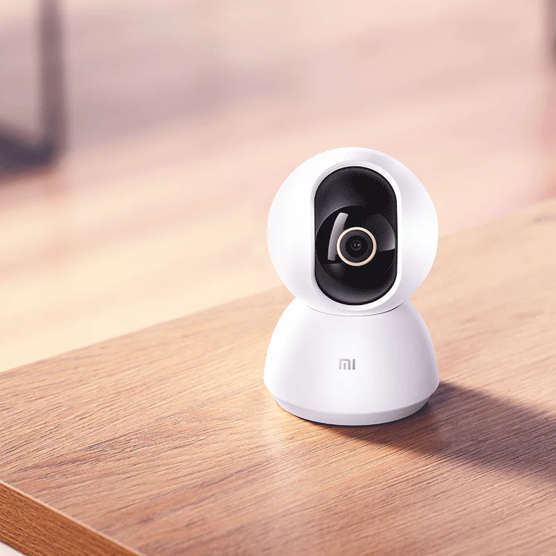 Домашняя смарт-камера белого цвета на деревянном столе.